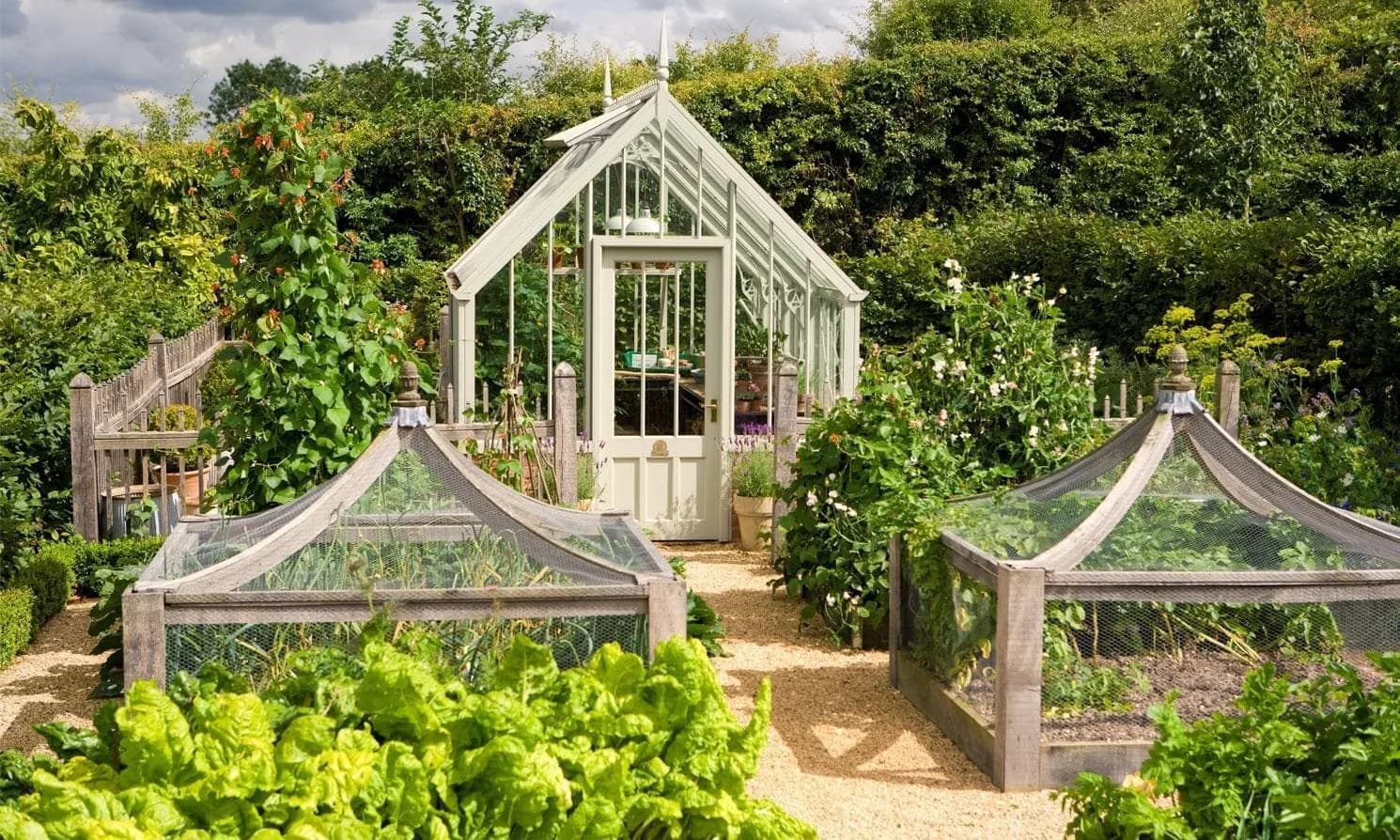 Sage green Alitex Victorian greenhouse with finials in a kitchen garden with netted fruit cages