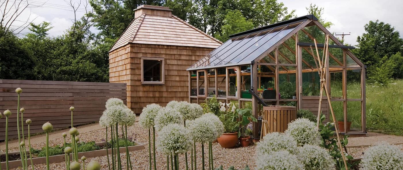 Gabriel Ash Classic cedar greenhouse beside a shingled potting shed in a kitchen garden