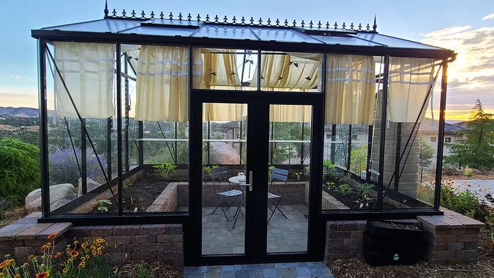 Janssens Royal Victorian greenhouse with cream shade curtains and interior raised beds at sunset