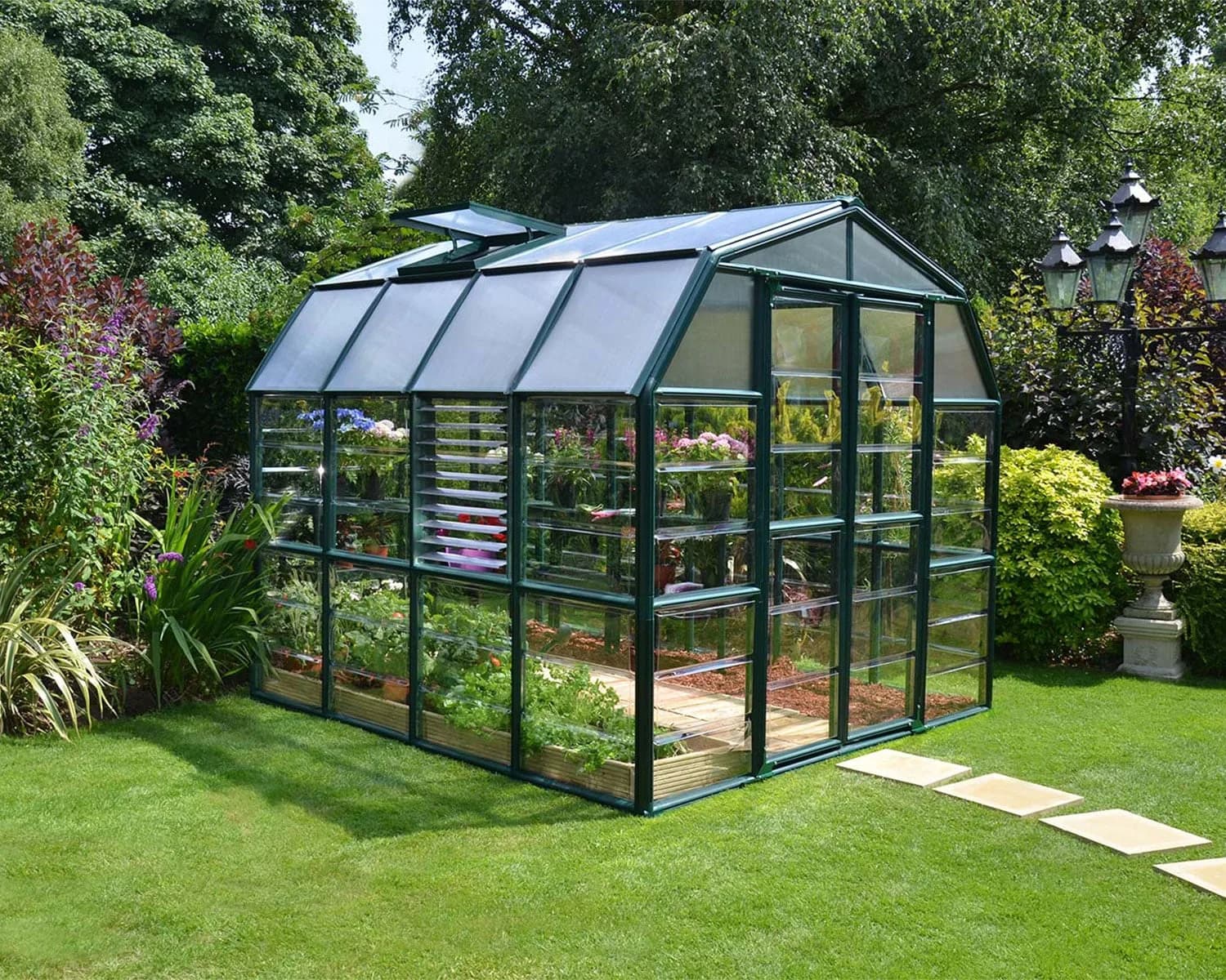 Rion Prestige greenhouse with clear glazing, green frame and open roof vent in a garden