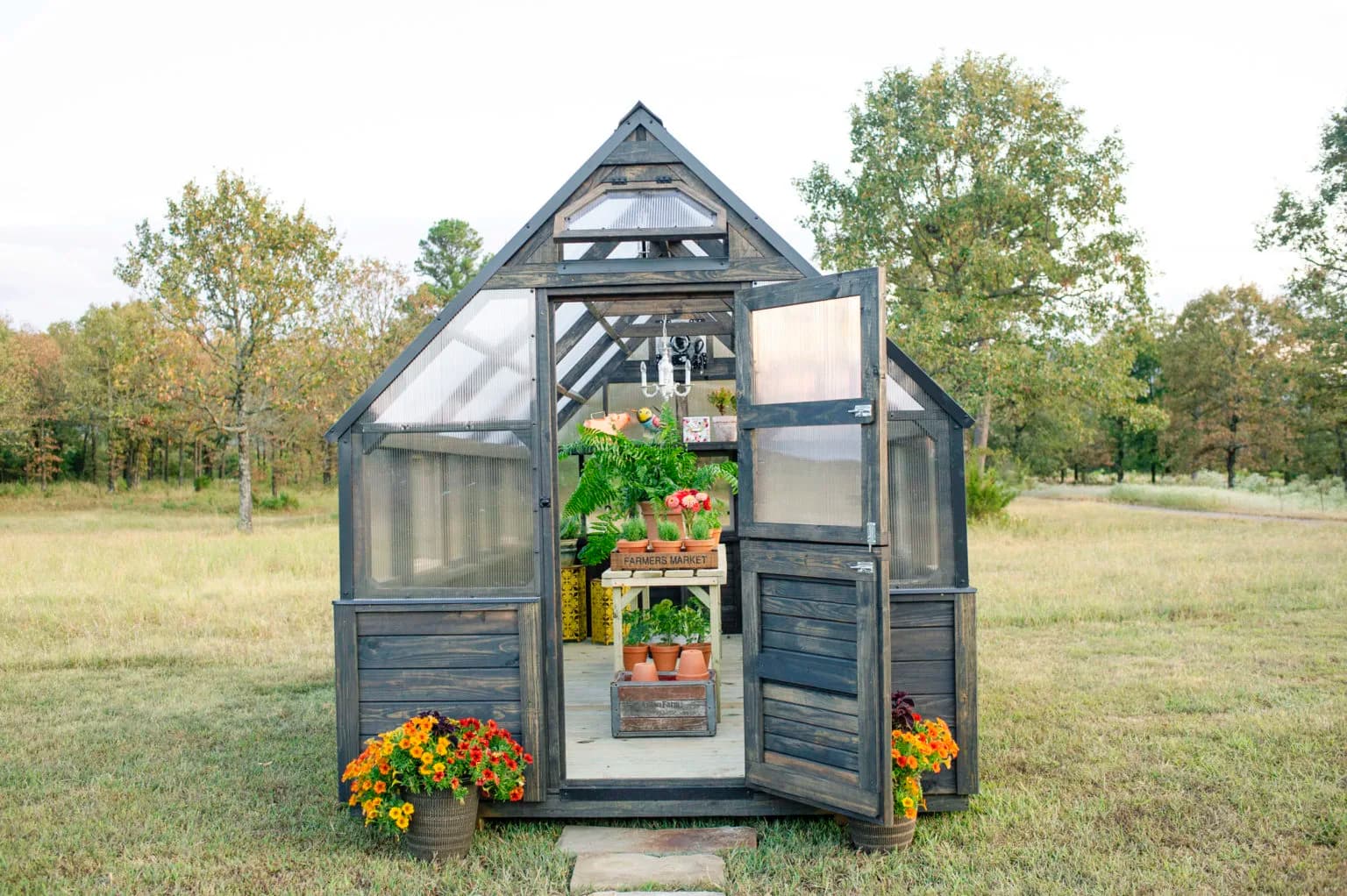 Dark-stained Yoderbilt greenhouse with polycarbonate panels standing in an open field